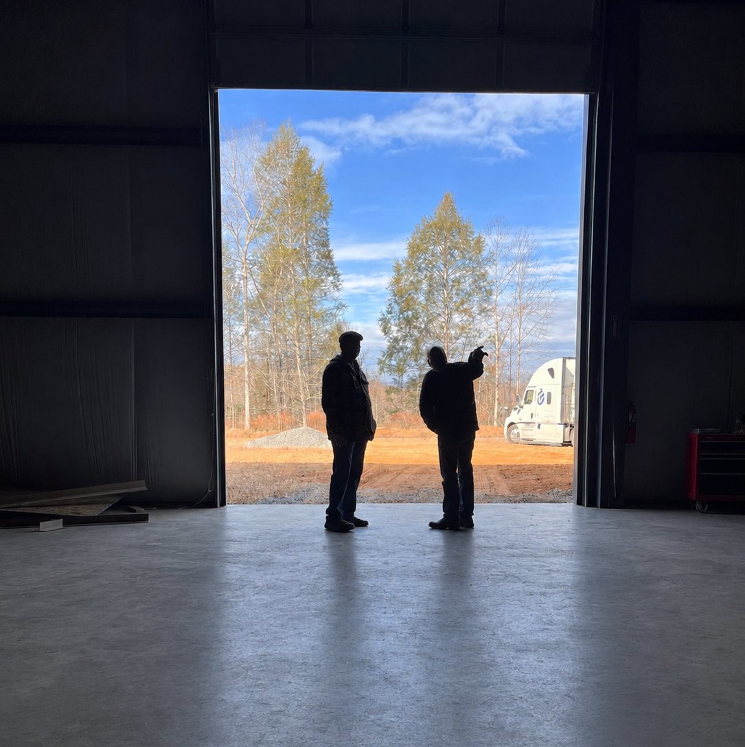 Dan Hodges and Dr. John Holliday in silhouette at the open bay door of the Highland facility, looking out at the Marion, NC property